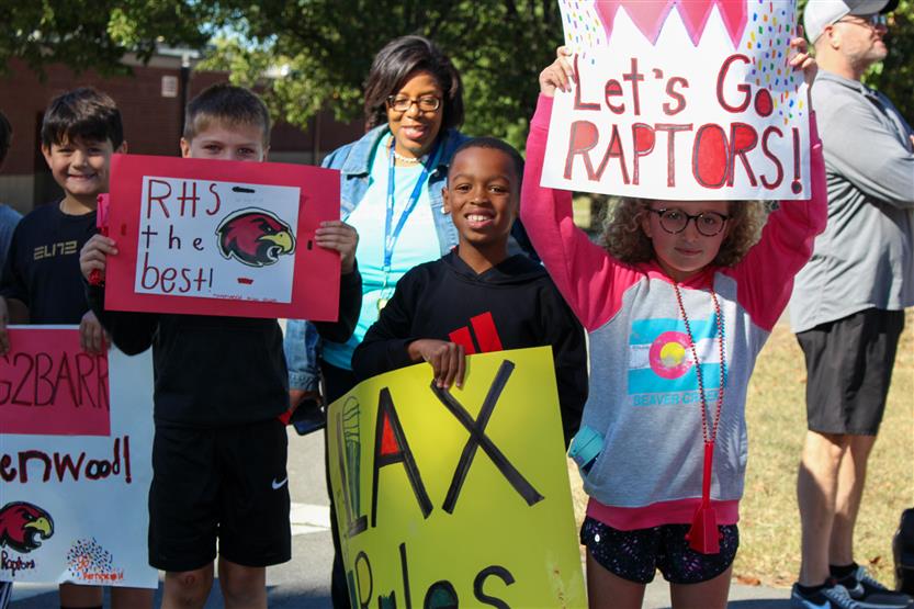 Students hold up signs for the Ravenwood High homecoming parade